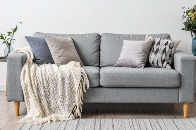 Un canapé gris confortable et décoré de coussins pour aider à choisir son futur canapé.