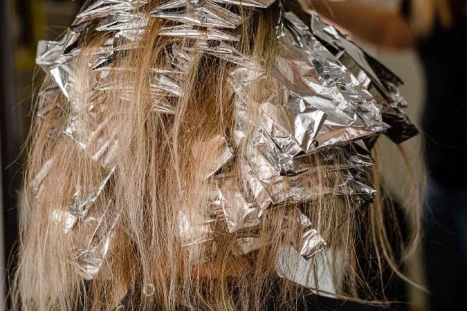 Cheveux d'une personne recouverts de papiers aluminium lors du processus de coloration pour obtenir des cheveux décolorés.